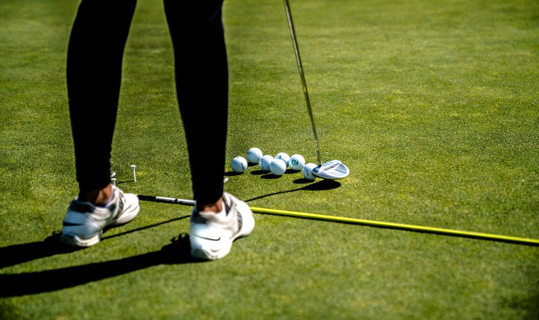 Junge weibliche Golferin, die mit einem Odyssey Putter auf dem Green steht und Golfbälle spielt.